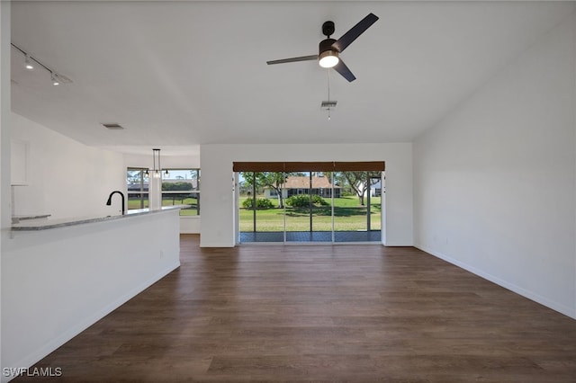 unfurnished living room with ceiling fan with notable chandelier, dark hardwood / wood-style flooring, and rail lighting