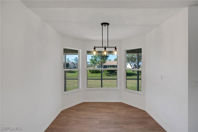 unfurnished dining area with a notable chandelier and hardwood / wood-style flooring