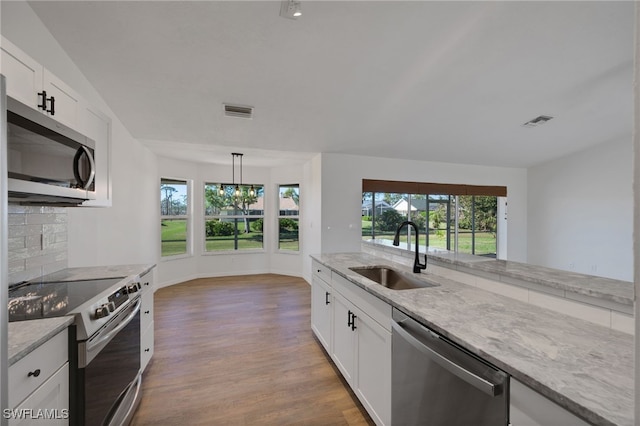 kitchen featuring appliances with stainless steel finishes, white cabinetry, a wealth of natural light, and sink