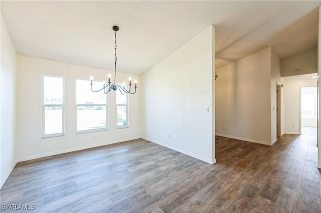 unfurnished dining area with dark hardwood / wood-style floors, vaulted ceiling, and a notable chandelier