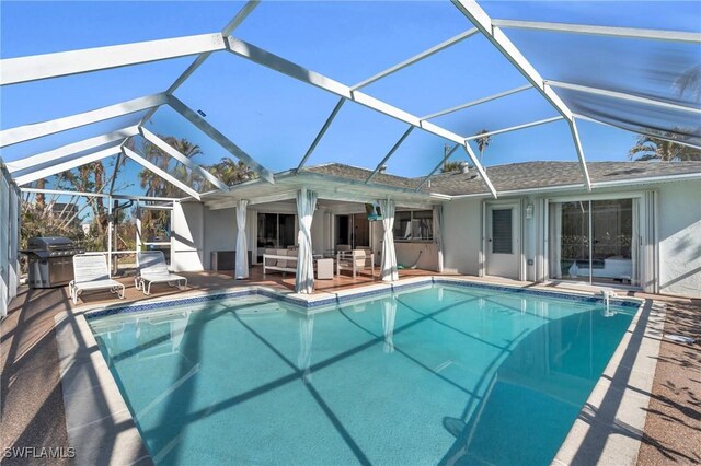 view of pool featuring an outdoor living space, glass enclosure, grilling area, and a patio area