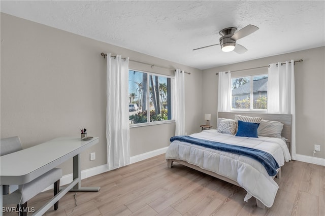 bedroom with a textured ceiling, light hardwood / wood-style floors, and ceiling fan