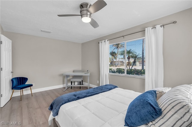 bedroom featuring light wood finished floors, visible vents, ceiling fan, a textured ceiling, and baseboards