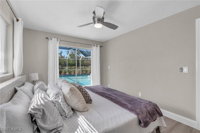 bedroom featuring ceiling fan, wood finished floors, a sunroom, baseboards, and access to exterior