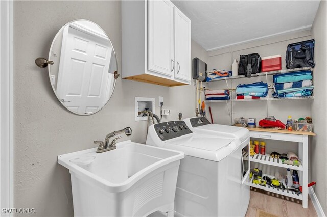 laundry area featuring washer and clothes dryer, cabinets, light wood-type flooring, and sink