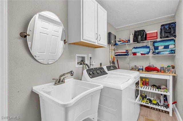 washroom with washer and dryer, cabinet space, a sink, and light wood-style flooring