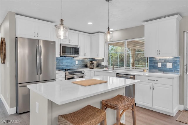 kitchen with a kitchen island, stainless steel appliances, light countertops, and decorative light fixtures