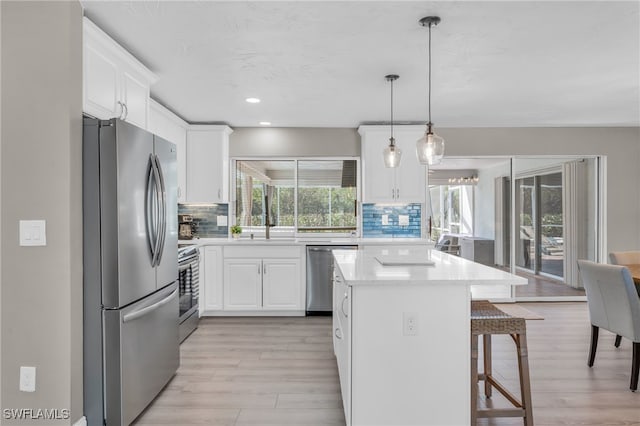 kitchen featuring pendant lighting, decorative backsplash, white cabinets, and appliances with stainless steel finishes