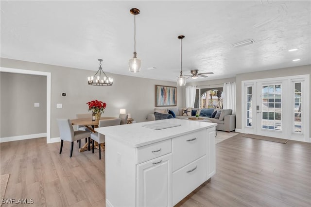 kitchen with a kitchen island, open floor plan, light countertops, white cabinetry, and pendant lighting