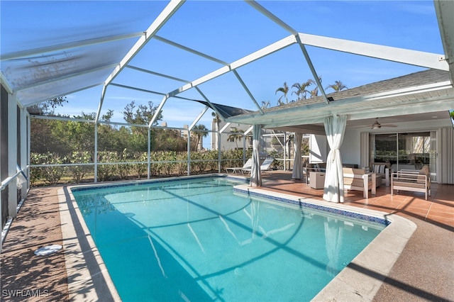 view of swimming pool with glass enclosure, ceiling fan, and a patio