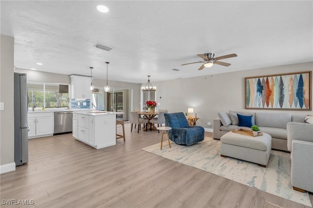 living room featuring recessed lighting, visible vents, light wood-style floors, baseboards, and ceiling fan with notable chandelier