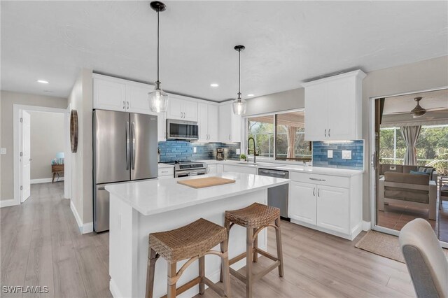 kitchen with hanging light fixtures, a center island, light hardwood / wood-style floors, and appliances with stainless steel finishes