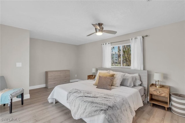 bedroom featuring ceiling fan, light wood finished floors, and baseboards