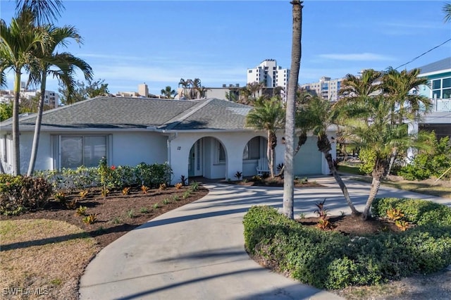 ranch-style home featuring concrete driveway, roof with shingles, an attached garage, and stucco siding