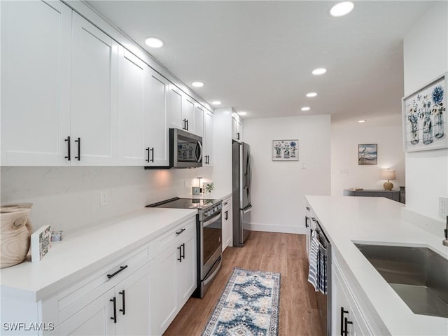 kitchen featuring white cabinets, sink, appliances with stainless steel finishes, and light hardwood / wood-style flooring