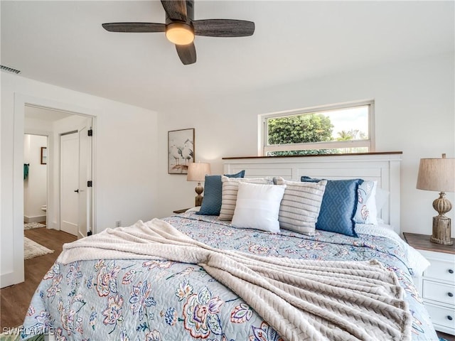 bedroom with ensuite bath, ceiling fan, and dark hardwood / wood-style flooring