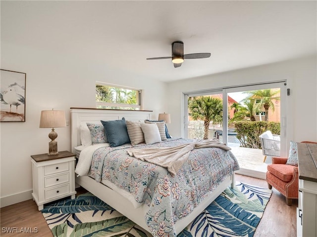 bedroom with ceiling fan, access to exterior, wood-type flooring, and multiple windows