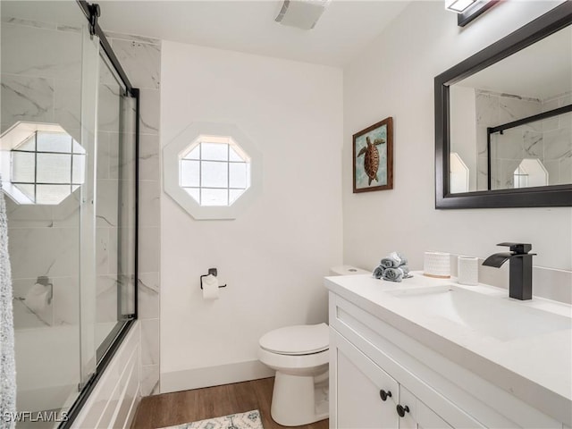 full bathroom with hardwood / wood-style flooring, vanity, toilet, and bath / shower combo with glass door