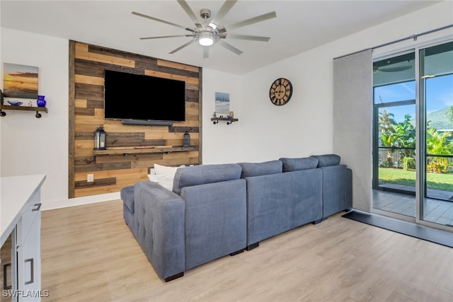 living room with wood walls, light hardwood / wood-style flooring, and ceiling fan