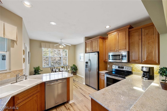 kitchen featuring backsplash, sink, light hardwood / wood-style flooring, and appliances with stainless steel finishes