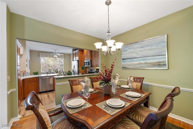 dining room featuring ceiling fan with notable chandelier, light wood-type flooring, and sink