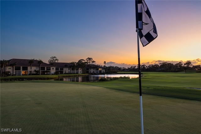 surrounding community with a water view and a lawn