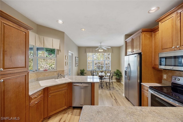 kitchen featuring appliances with stainless steel finishes, light hardwood / wood-style flooring, plenty of natural light, and sink