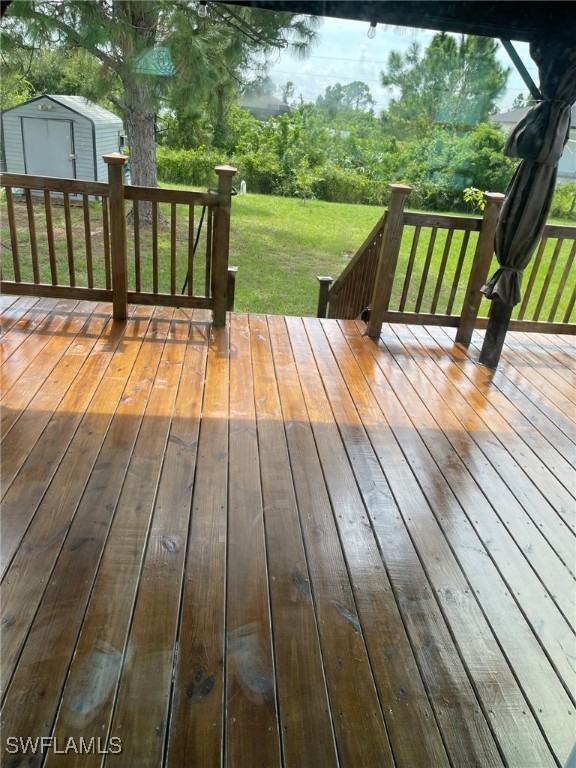 wooden terrace featuring a storage shed and a lawn