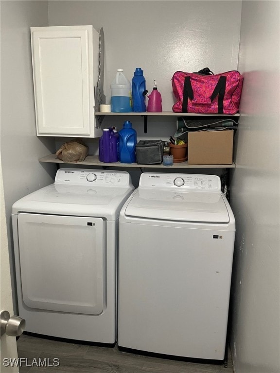 clothes washing area featuring cabinets, washing machine and dryer, and dark hardwood / wood-style floors