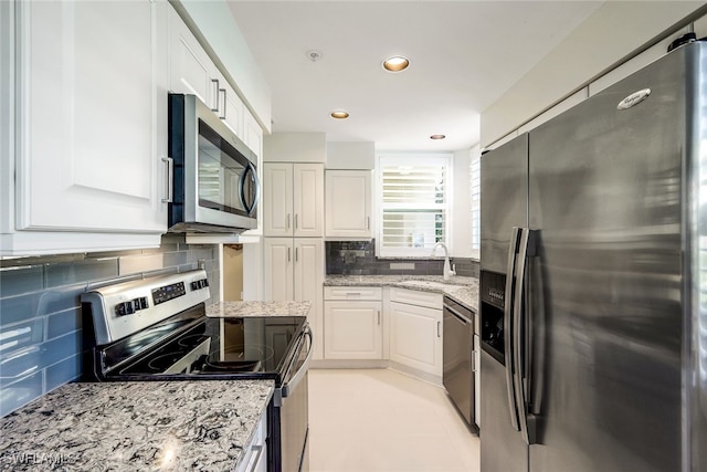 kitchen with white cabinetry, sink, tasteful backsplash, light stone counters, and appliances with stainless steel finishes