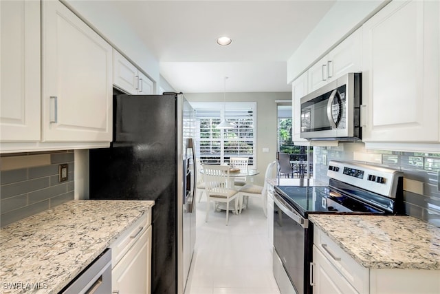 kitchen with white cabinets, decorative backsplash, pendant lighting, and stainless steel appliances