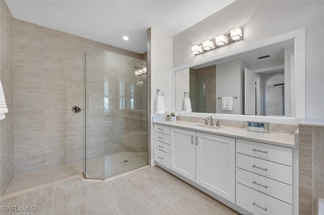 bathroom with tiled shower and vanity