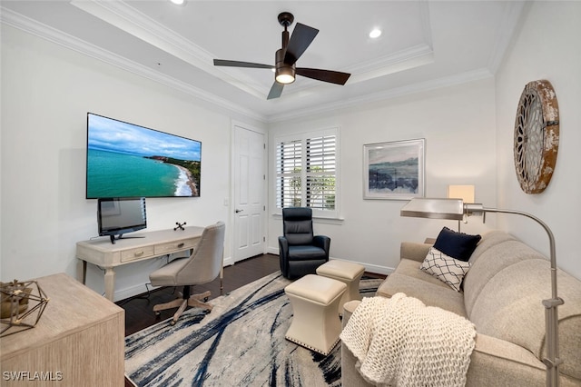 home office with crown molding, dark wood-type flooring, ceiling fan, and a tray ceiling