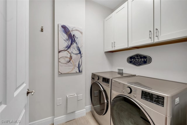 clothes washing area with cabinets and washing machine and dryer