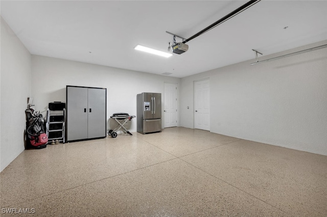 garage featuring a garage door opener and stainless steel fridge