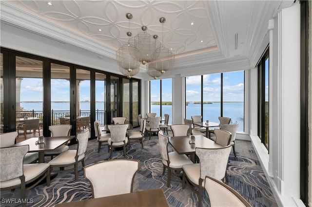 sunroom featuring french doors, a water view, and a tray ceiling