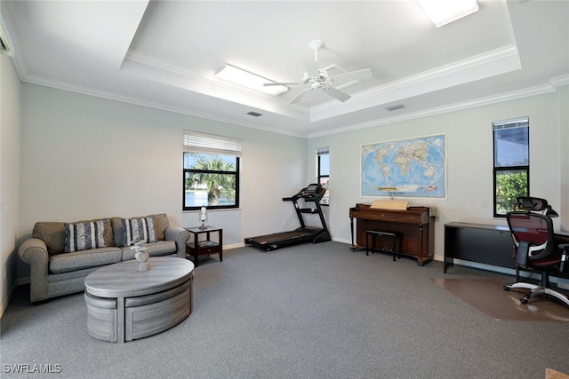 interior space featuring a raised ceiling, crown molding, carpet floors, and ceiling fan