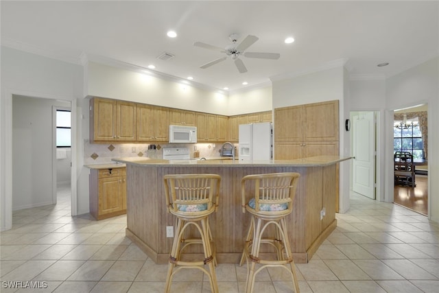 kitchen with a center island with sink, a breakfast bar, white appliances, and ornamental molding