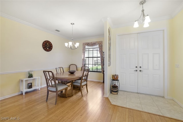 dining space with light wood-type flooring, crown molding, and a notable chandelier