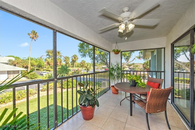 sunroom / solarium featuring ceiling fan and a water view