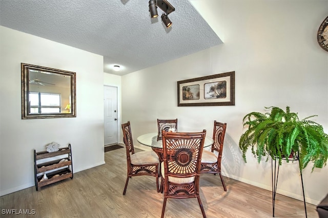 dining space with a textured ceiling and light hardwood / wood-style flooring