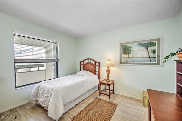 bedroom with a textured ceiling and light wood-type flooring