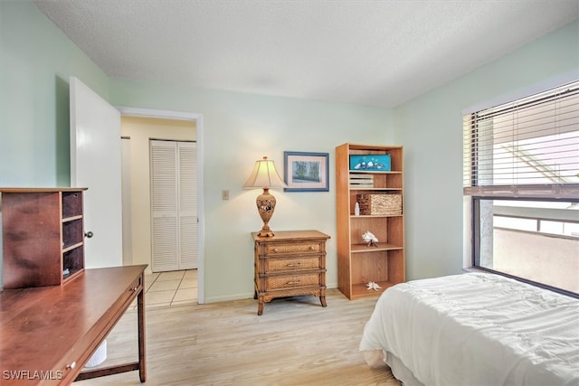 bedroom with a closet, a textured ceiling, and light wood-type flooring