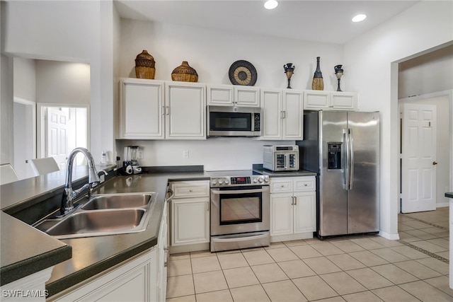 kitchen with appliances with stainless steel finishes, white cabinetry, light tile patterned floors, and sink