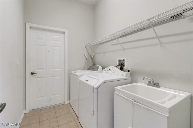 clothes washing area featuring washing machine and dryer, light tile patterned floors, and sink