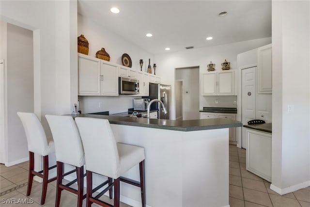 kitchen featuring kitchen peninsula, white cabinets, light tile patterned floors, and appliances with stainless steel finishes