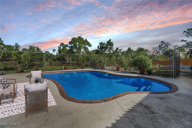 pool at dusk with a patio area