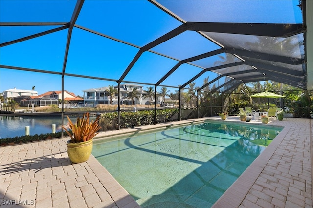 view of pool with glass enclosure, a patio area, and a water view