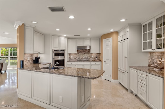 kitchen with stone counters, stainless steel double oven, and white cabinets