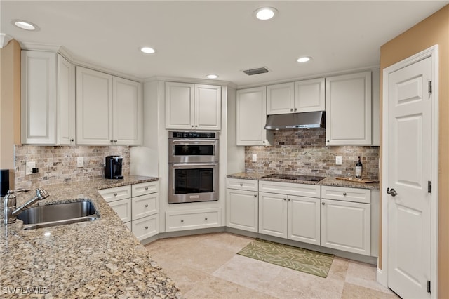 kitchen featuring light stone countertops, stainless steel double oven, white cabinetry, and sink